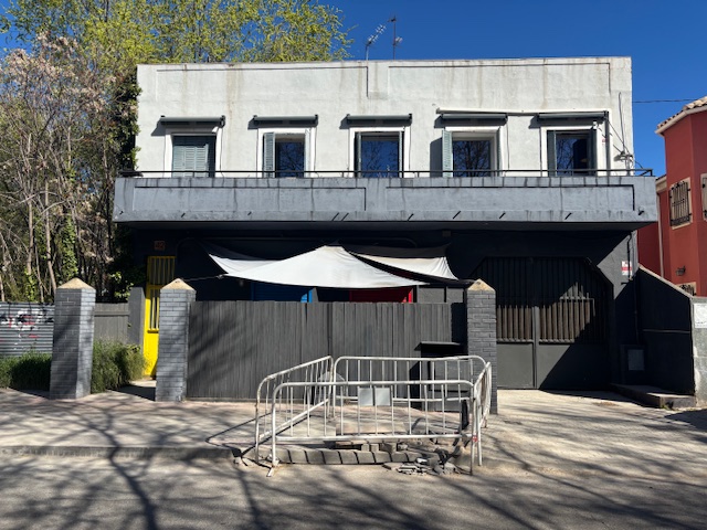 Fachada de Plató La Mina en Calle Joaquín Lorenzo 42, Madrid, con puerta peatonal amarilla y portón de carruajes