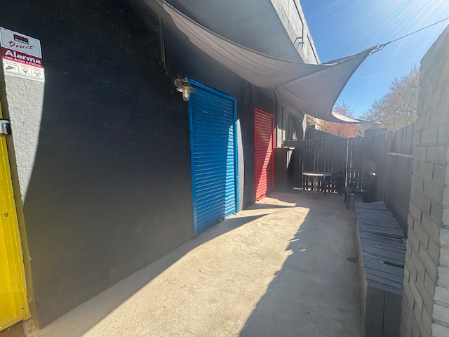 Patio exterior privado de Plató La Mina con toldo de sombra, portones de colores y zona de descanso