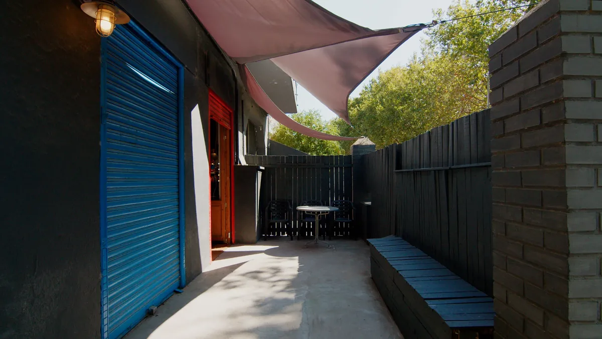 Private outdoor patio at Plató La Mina with a shade awning, a blue door and a seating area